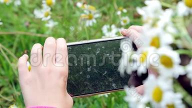 特写镜头，一个女孩拿着手机，拿着手机，给他们拍照，给一个小草坪拍照